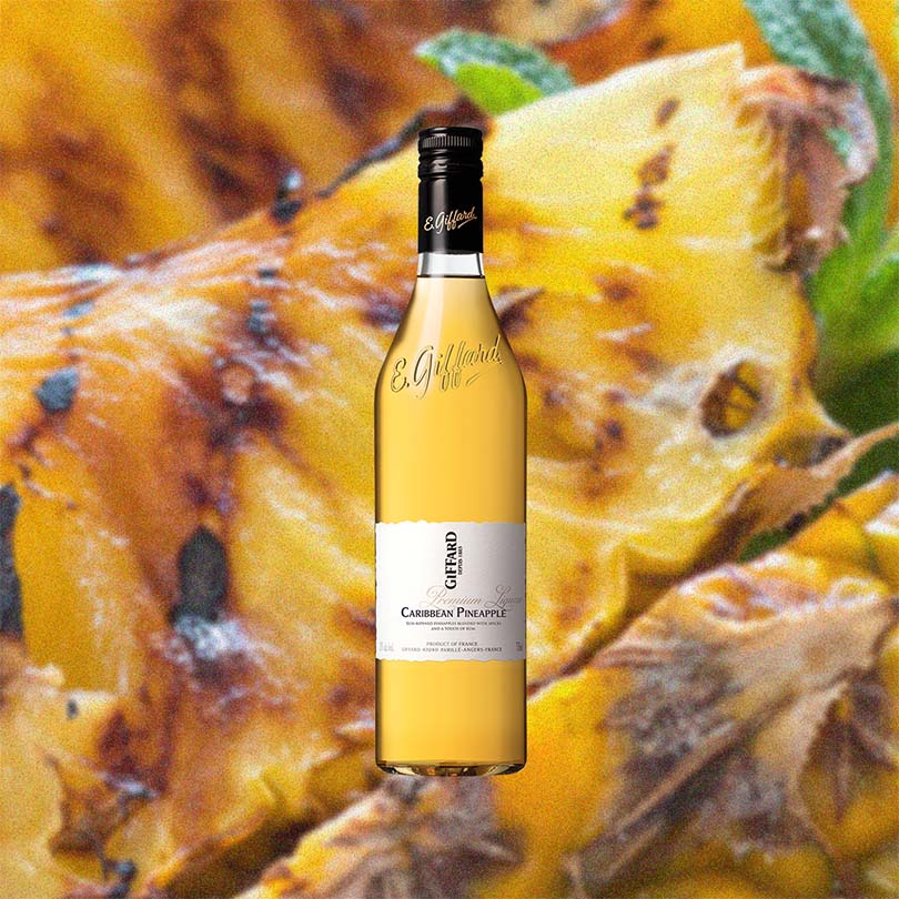 Bottle of Giffard Caribbean Pineapple Liqueur over backdrop image of pineapple.