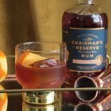 Chairman's Reserve Rum bottle with a cocktail in a glass on a reflective surface.