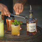 Person grating a lime over a cocktail with Chairman's Reserve Rum bottle in the background