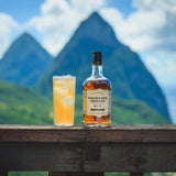 Chairman's Reserve rum bottle with a cocktail on a wooden ledge against a mountainous background