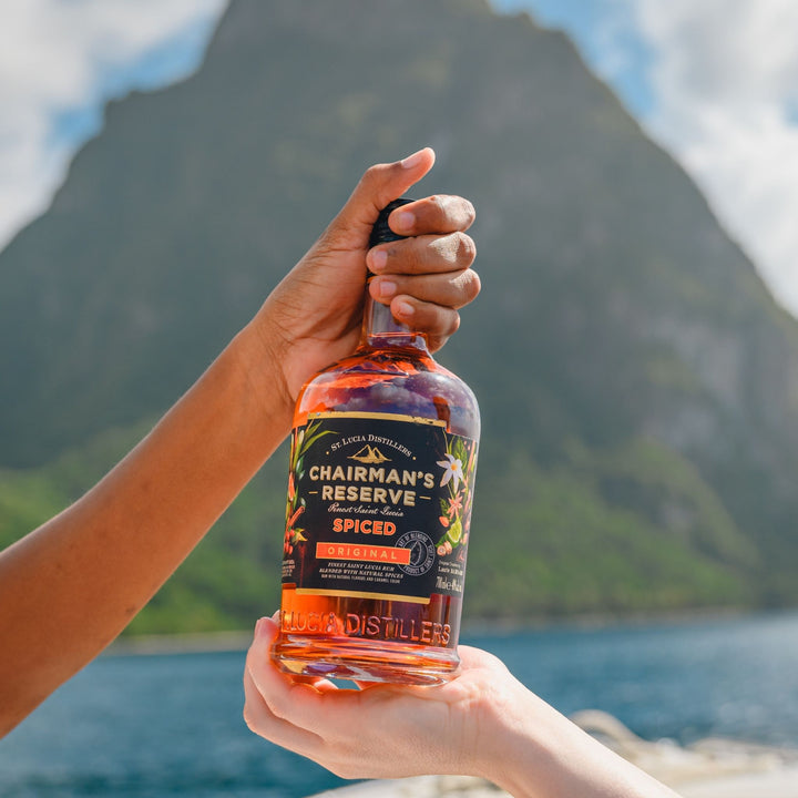 Person holding a bottle of Chairman's Reserve Spiced rum with a scenic background