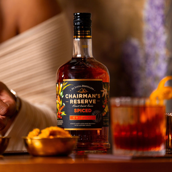 Chairman's Reserve Spiced rum bottle with a glass of rum on a wooden surface.