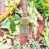 Bottle of Chartreuse Vegetal de La Grande (Chartreuse Elixir Vegetal) over backdrop of greenery and what appears to be a wooden fence.