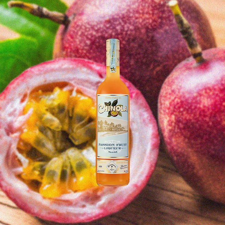 Bottle of Chinola Passionfruit Liqueur over backdrop image of passion fruits.