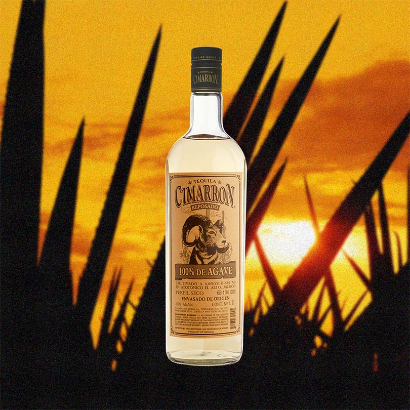A bottle of Cimarron Reposado Tequila with a label showcasing the brand name and a graphic of a dragon, against a background of a sunset.