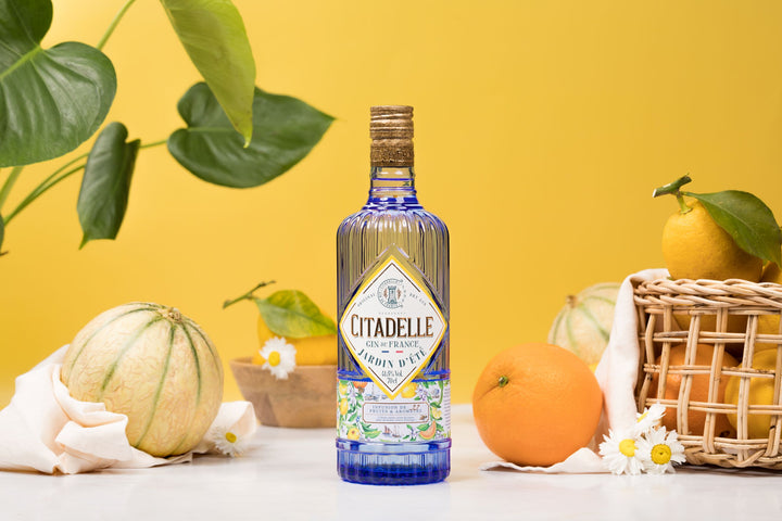 Citadelle gin bottle with fruits and plants on a yellow background