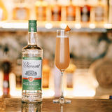 Bottle of Clément Martiniquè rum with a cocktail in a glass on a bar counter.