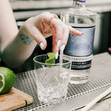 Person preparing a cocktail with a bottle of Célèment rum in the background.
