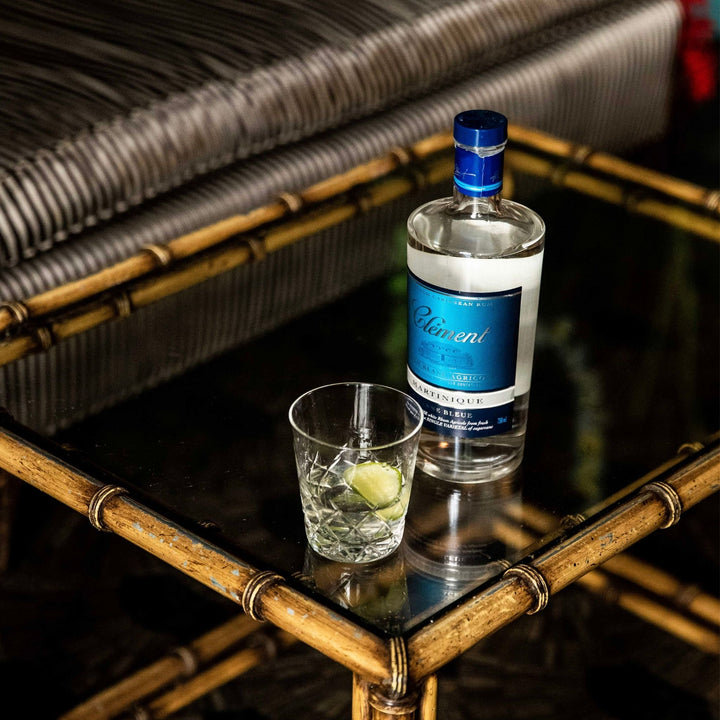 Bottle of Belvedere vodka and a glass with a lime wedge on a reflective surface.