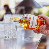 Person pouring Creole Shrubs into a glass outdoors