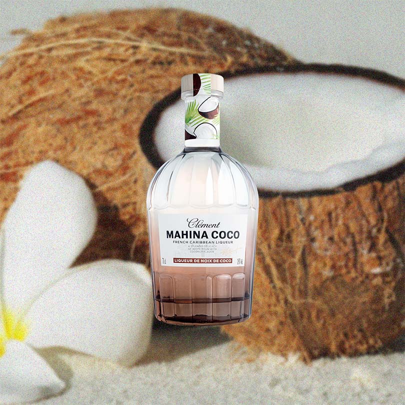 Bottle of Rhum Clement Mahina Coco Liqueur over back drop image of coconuts.