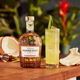 Bottle of Mahina Coco rum with a cocktail on a wooden surface, surrounded by tropical elements.