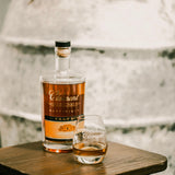Bottle and glass of Clement rum on a wooden surface with a blurred natural background