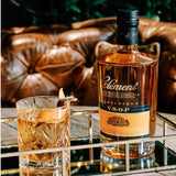 Bottle of H. Clement Martinique V.S.O.P. cognac with a glass on a reflective surface.