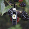 Bottle of Combier Crème de Mûre Blackberry Liqueur over back drop image of black berries.