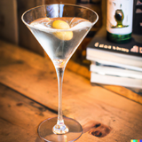 An Elyx Martini cocktail with Absolut Elyx Vodka sitting on a wooden table in the style of a contemporary cocktail recipe book..