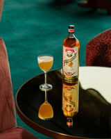 Bottle and glass of alcohol on a reflective surface with a blurred background