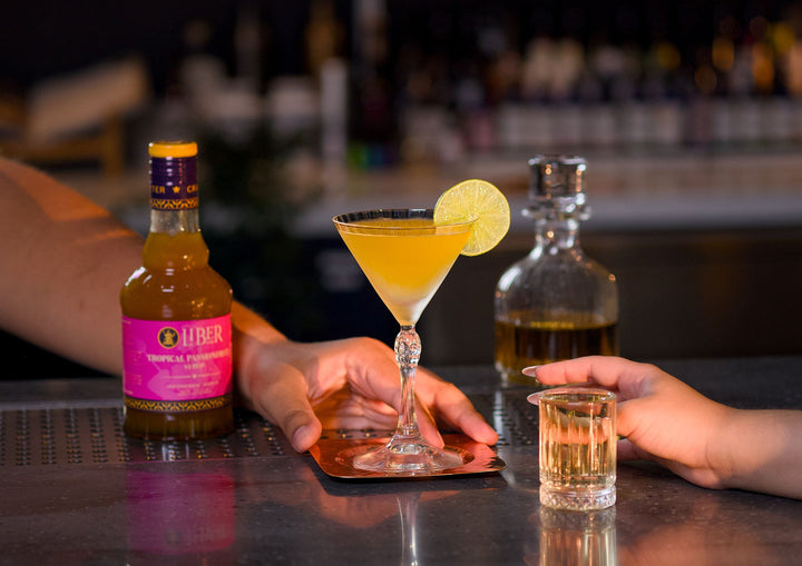 Cocktail with a bottle of Liber & Co Syrup on a bar counter