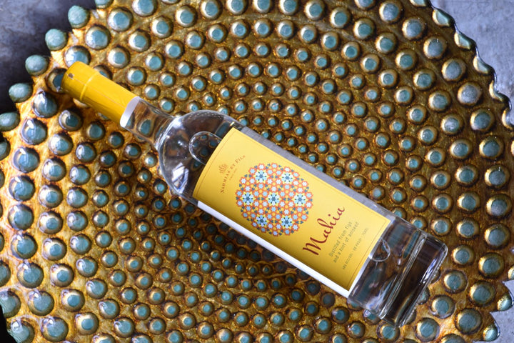 Bottle of Mahia Fig Spirit on a textured surface with a decorative pattern.