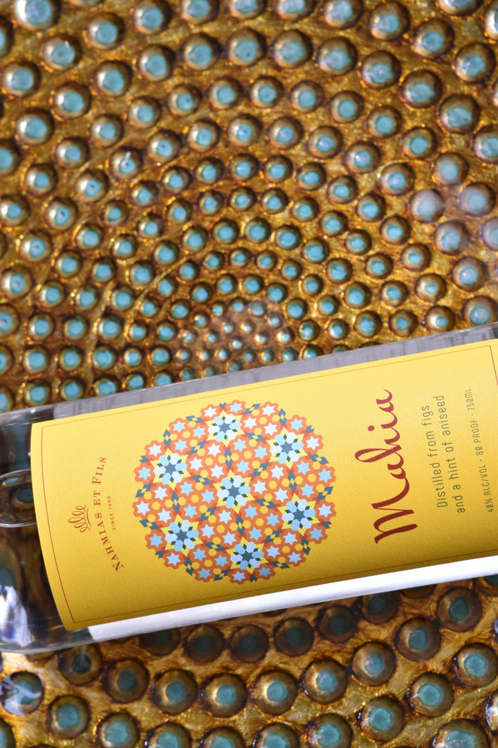 Bottle of Mahia Fig Liqueur with decorative label on a textured surface
