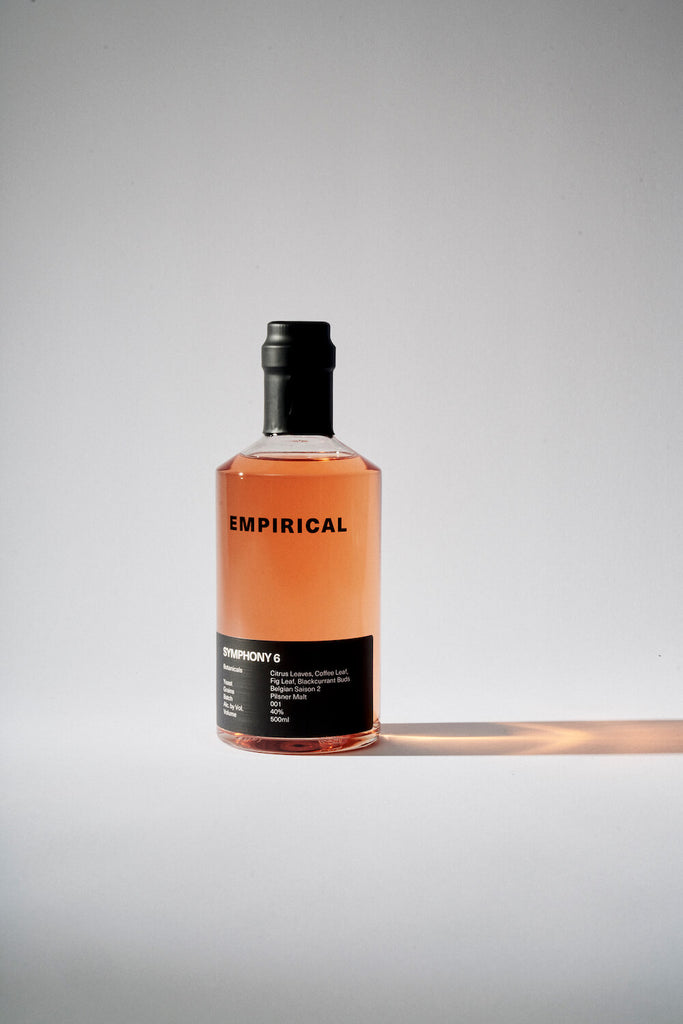 A lone bottle of Empirical Symphony 6, casting a long pink shadow. The backdrop is white, austere.