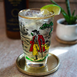 Decorative glass with a pirate design on a table with a plant in the background
