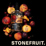 Bottle of Empirical Stonefruit spirit surrounded by stone fruits on a black background