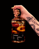 Hand holding a bottle labeled 'Empirical' with stonefruit flavor against a black background