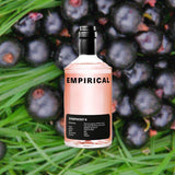 A bottle of Empirical Symphony 6 set against a macro shot of black current berries on a bed of bright grass.