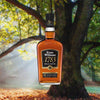 Bottle of Evan Williams 1783 Small Batch Bourbon over backdrop image of a tree in a forest on a sunny day.