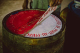 Close-up of a barrel with red and white labels, held by a person.
