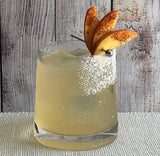 Cocktail with pear slices and a cherry on a wooden surface