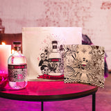 Espolón tequila bottle with decorative packaging on a table with a pink candle.