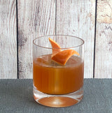 Glass of orange juice with a slice of orange on a wooden surface