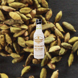 Bottle of Fee Brothers Cardamon Bitters over backdrop image of produce. 