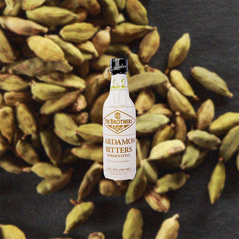Bottle of Fee Brothers Cardamon Bitters over backdrop image of produce. 