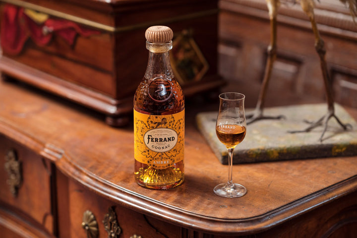 Ferrand cognac bottle and glass on a wooden surface with decorative background