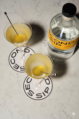 Bottle of Second Sip Gin on a table next to 2 martinis.