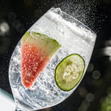 Ice cube with watermelon and cucumber slices on a dark background