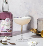 Gin Lane 1751 Violet bottle with a cocktail in a glass on a white surface.