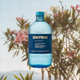 Bottle of Ginepraio Organic Mediterranean Dry Gin over backdrop image of a small tree with flowers.