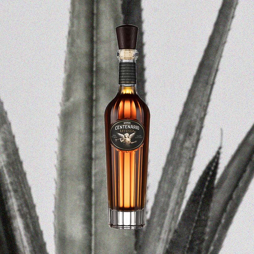 Bottle of Gran Centenario Leyenda Extra Anejo Tequila over backdrop image of agave.