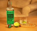 Bottle of Holmes Cay rum with a glass and lime on a wooden coaster.