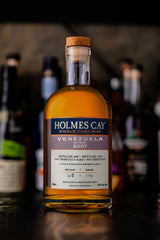 Bottle of Holmes Cay Venezuela 15 Year Single Cask Rum with a blurred bar background