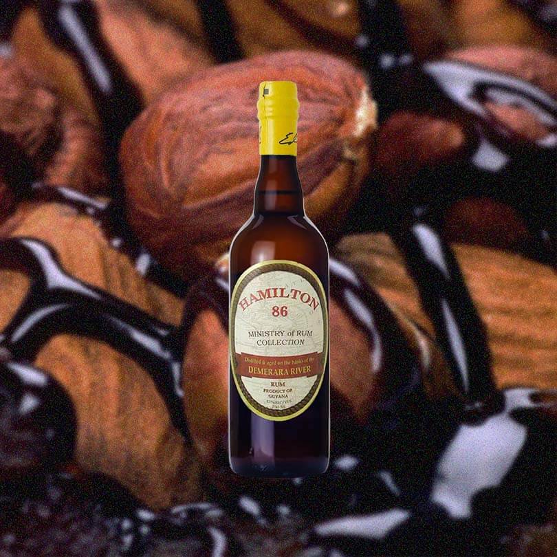 A bottle of Hamilton 86 on a backdrop of roasted nuts drizzled with chocolate.