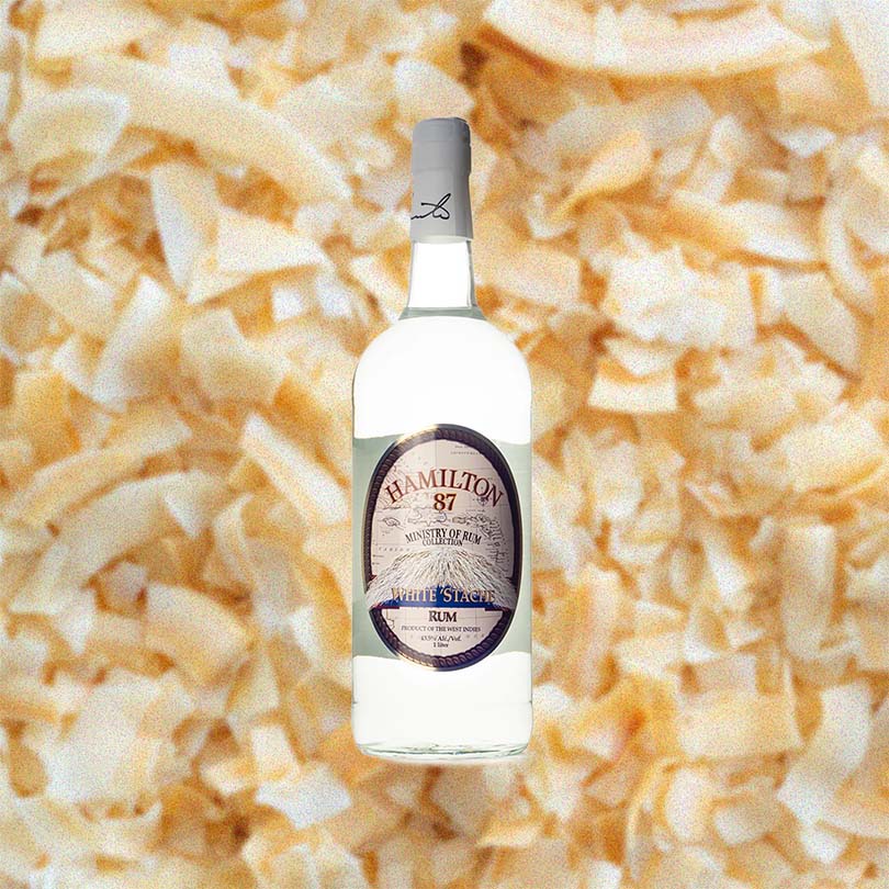Bottle of Hamilton 87 White Stache Rum over back drop image of coconut bits.