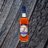 Bottle of Hamilton Beachbum Berry's Navy Grog Blend Rum over backdrop of blue wood.