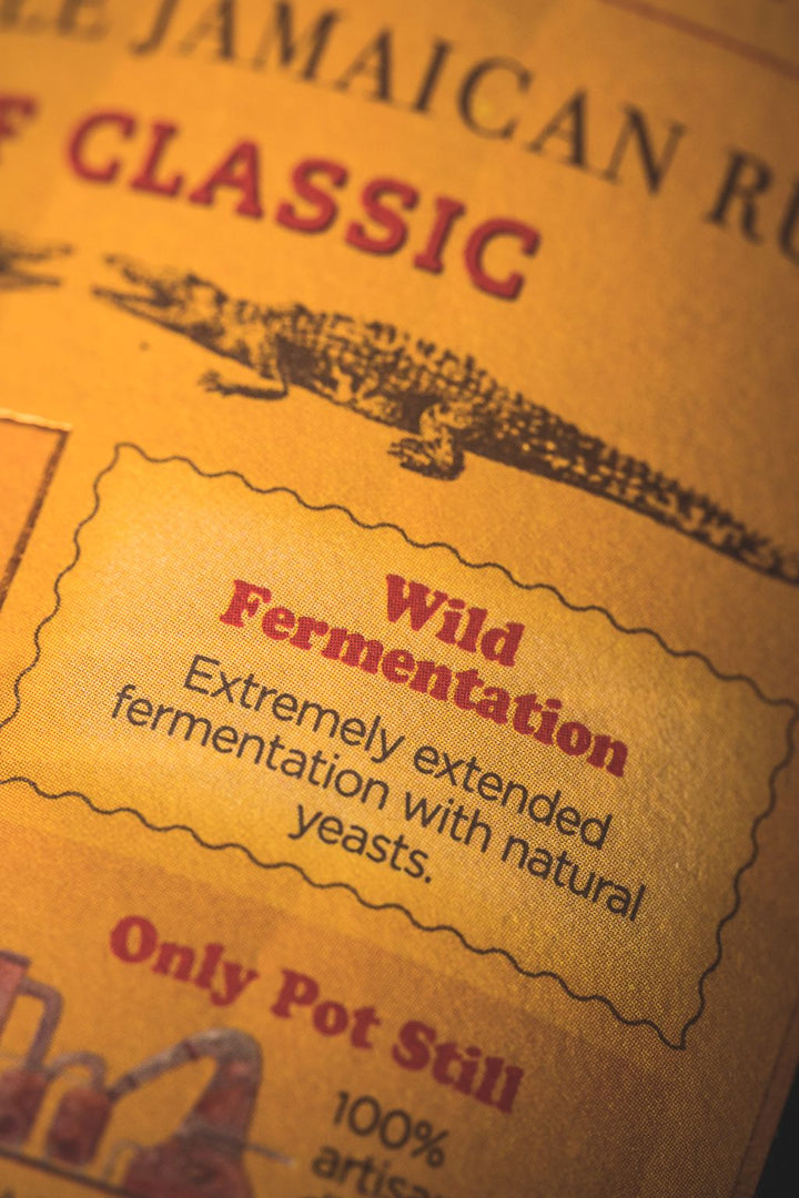 Close-up of a Jamaican rum label with text about wild fermentation and pot still distillation.