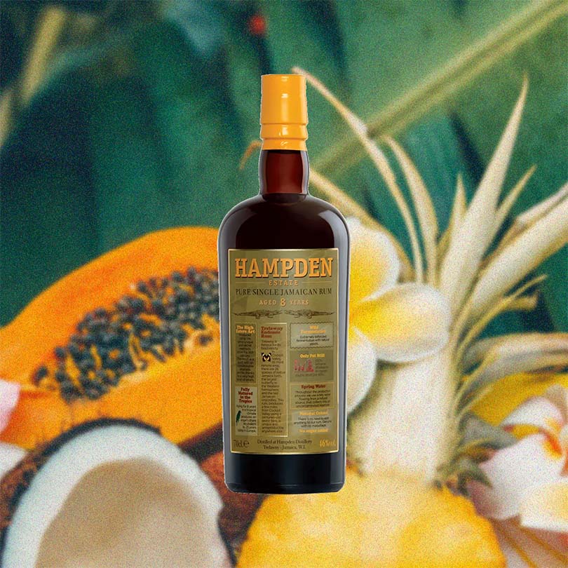 Bottle of Hampden Estate 8 Year Old Rum over backdrop image of various tropical fruits.