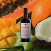 Bottle of Hampden Great House 2024 Distillery Edition over back drop image of coconut and fruits.